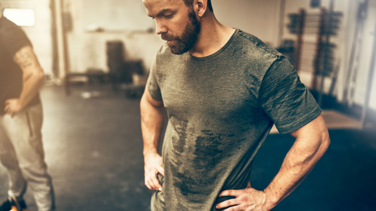 Muscular person resting in gym while sweating