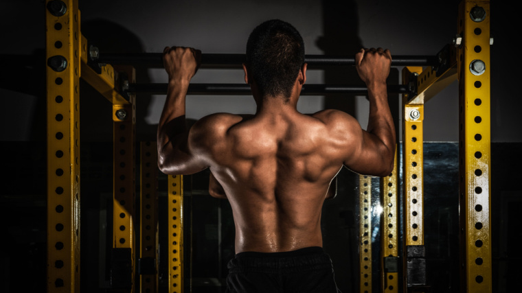 Muscular person performing pull-ups in gym