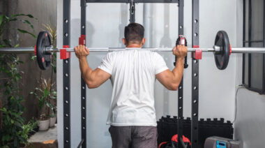 Muscular person standing in power rack holding barbell