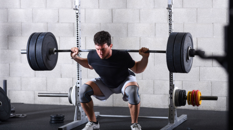 Person in gym performing barbell squat