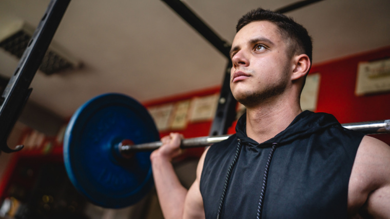 Muscular person in gym performing barbell squat