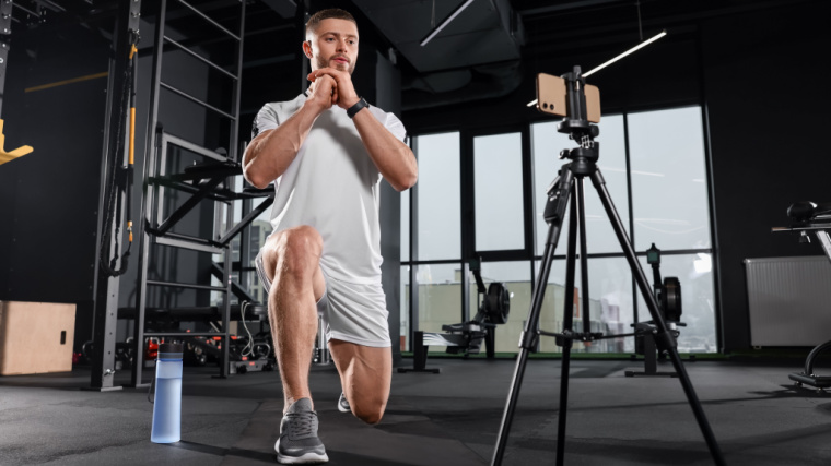 Person in gym doing lunges recording a video