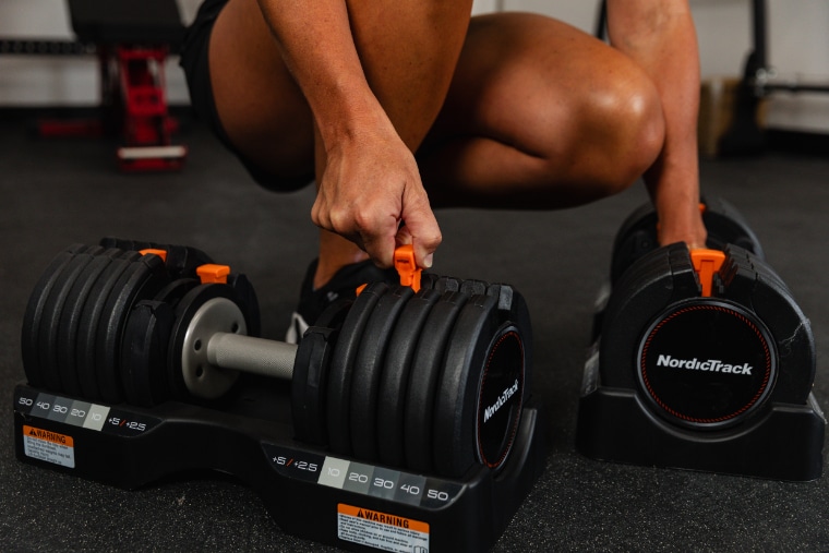An athlete adjusting the weight on the NordicTrack Select-a-Weight Dumbbells