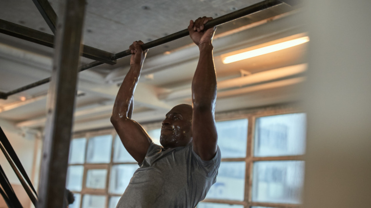 Muscular person in gym performing pull-up