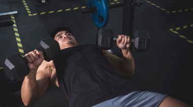 Person in gym doing dumbbell bench press