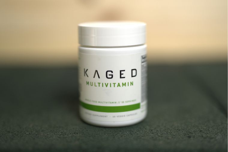 A bottle of Kaged multivitamin on a black surface with a wood background