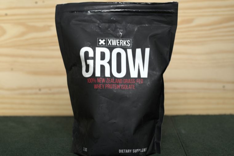 A bag of XWERKS Grow on a black surface with a wood background