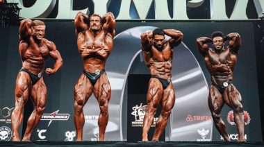 Chris Bumstead and other Classic Physique competitors pose on stage at the 2023 Mr. Olympia contest.