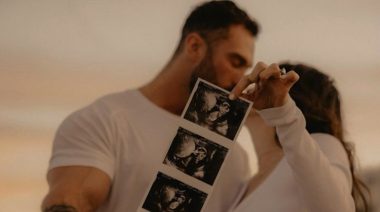 Chris Bumstead and fiancee Courtney King kiss as she holds up a sonogram of their baby.