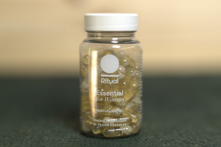 A container of Ritual's women's multivitamin on front of a wood background