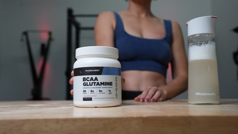 Woman holding a container of Transparent Lab BCAA Glutamine supplement.