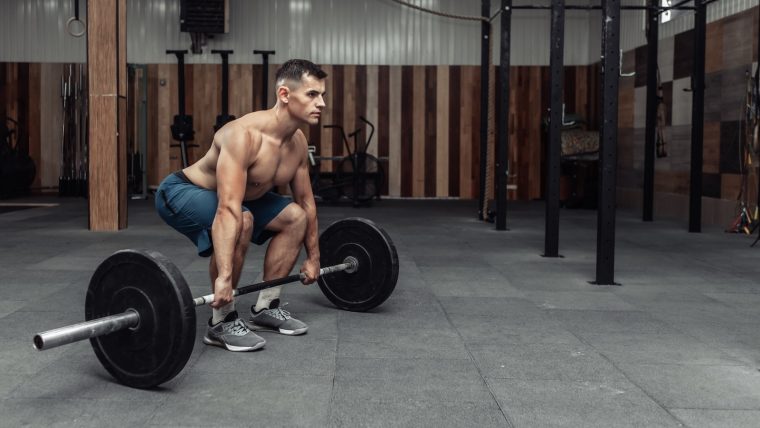 Man performs a conventional barbell deadlift.