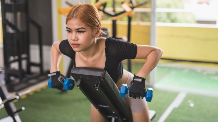 Woman performs a chest-supported row with dumbbells.