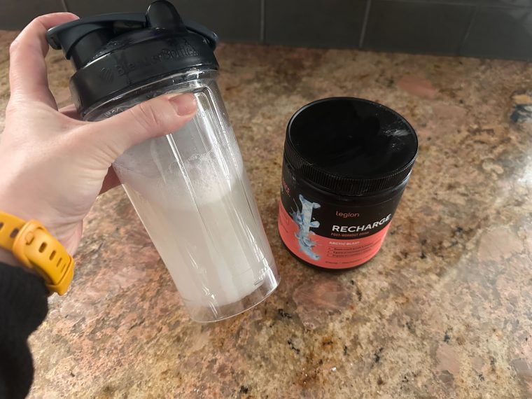 Woman shaking a shaker cup with a serving of Recharge creatine