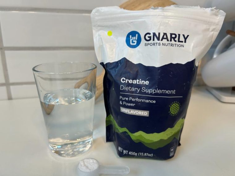 A bag of Gnarly Creatine next to a glass of water