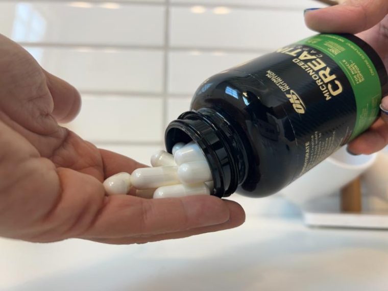 A woman pouring Optimum Nutrition Creatine Capsules into her hand