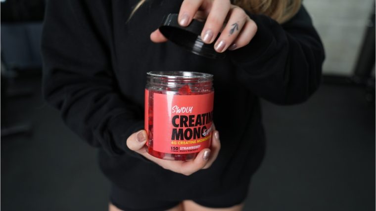 Woman holding a container of Swoly Creatine Gummies