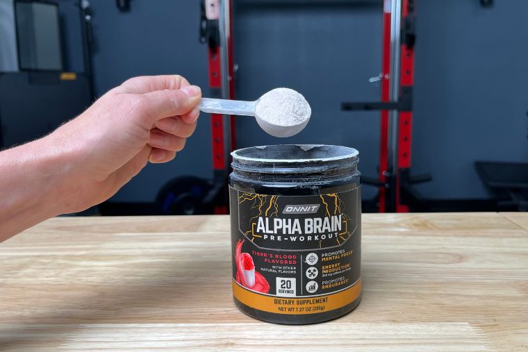 A person holding a scoop of Onnit Alpha Brain Pre-Workout