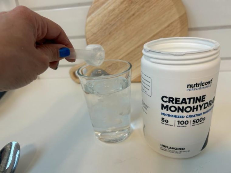 Pouring a scoop of Nutricost Creatine Monohydrate into a glass