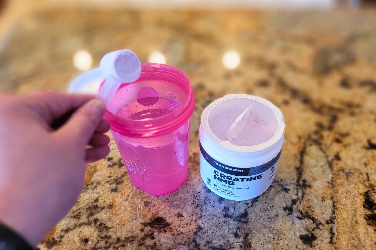 Pouring Transparent Labs Creatine HMB into a shaker bottle