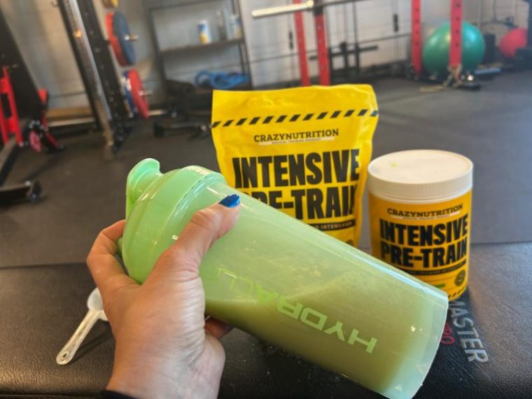 Person shaking a bottle filled with Scoop of Crazy Nutrition Intensive Pre-Train pre-workout