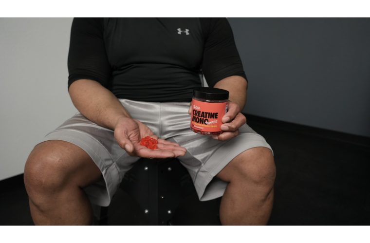 Man holding a handful of Swoly Creatine Gummies and a container