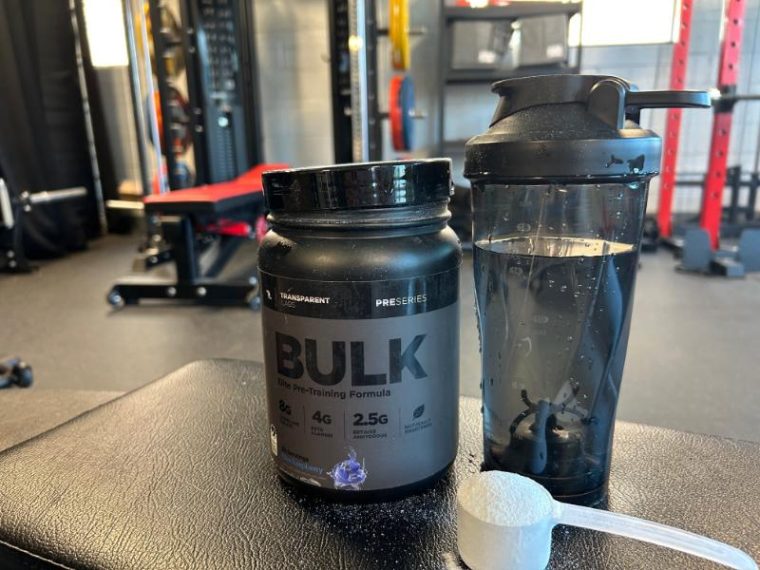 Container of Transparent Labs Bulk Black in the gym next to a shaker bottle